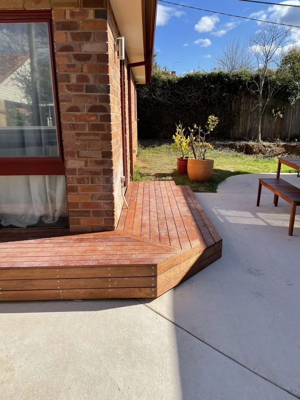 Custom hardwood deck wrapping around the cottage and connecting to the paved outdoor area