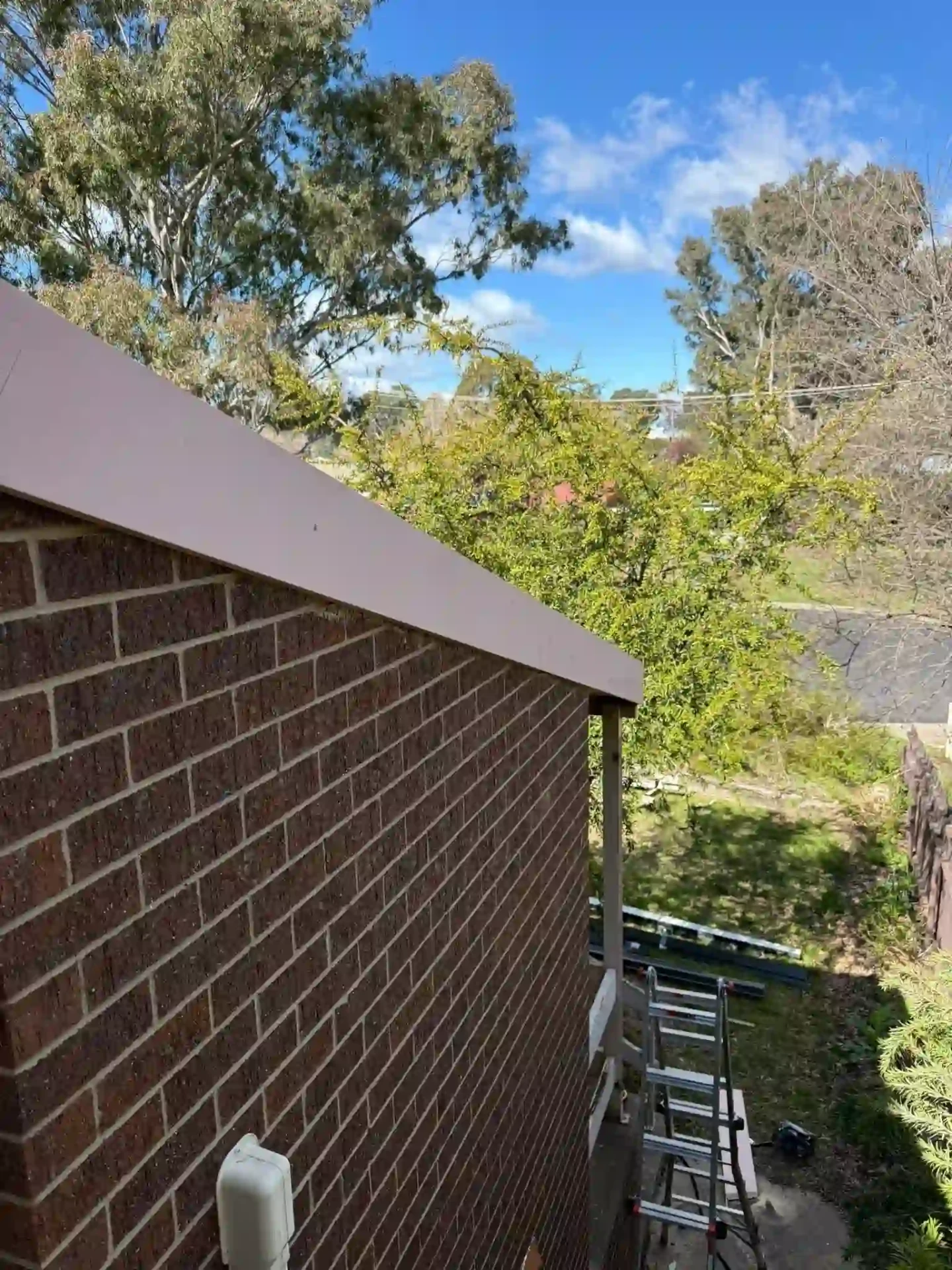 Rooftop view of new fascia and guttering on the Queanbeyan home with ladder below