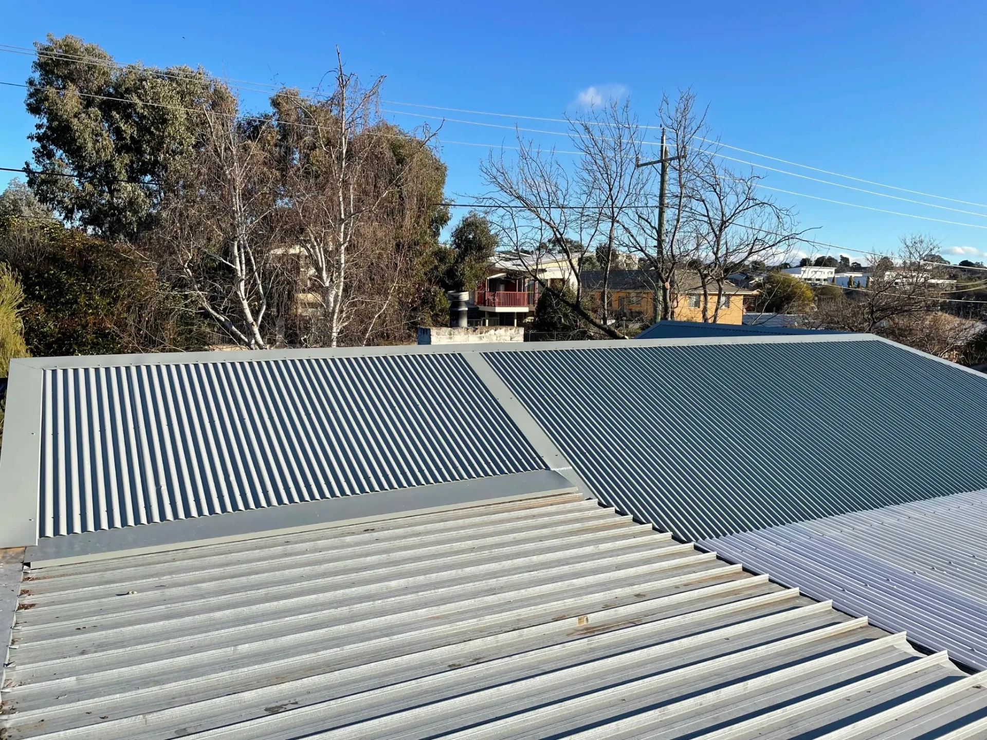 Wide view of the completed Oaks Estate metal roof under a clear blue sky