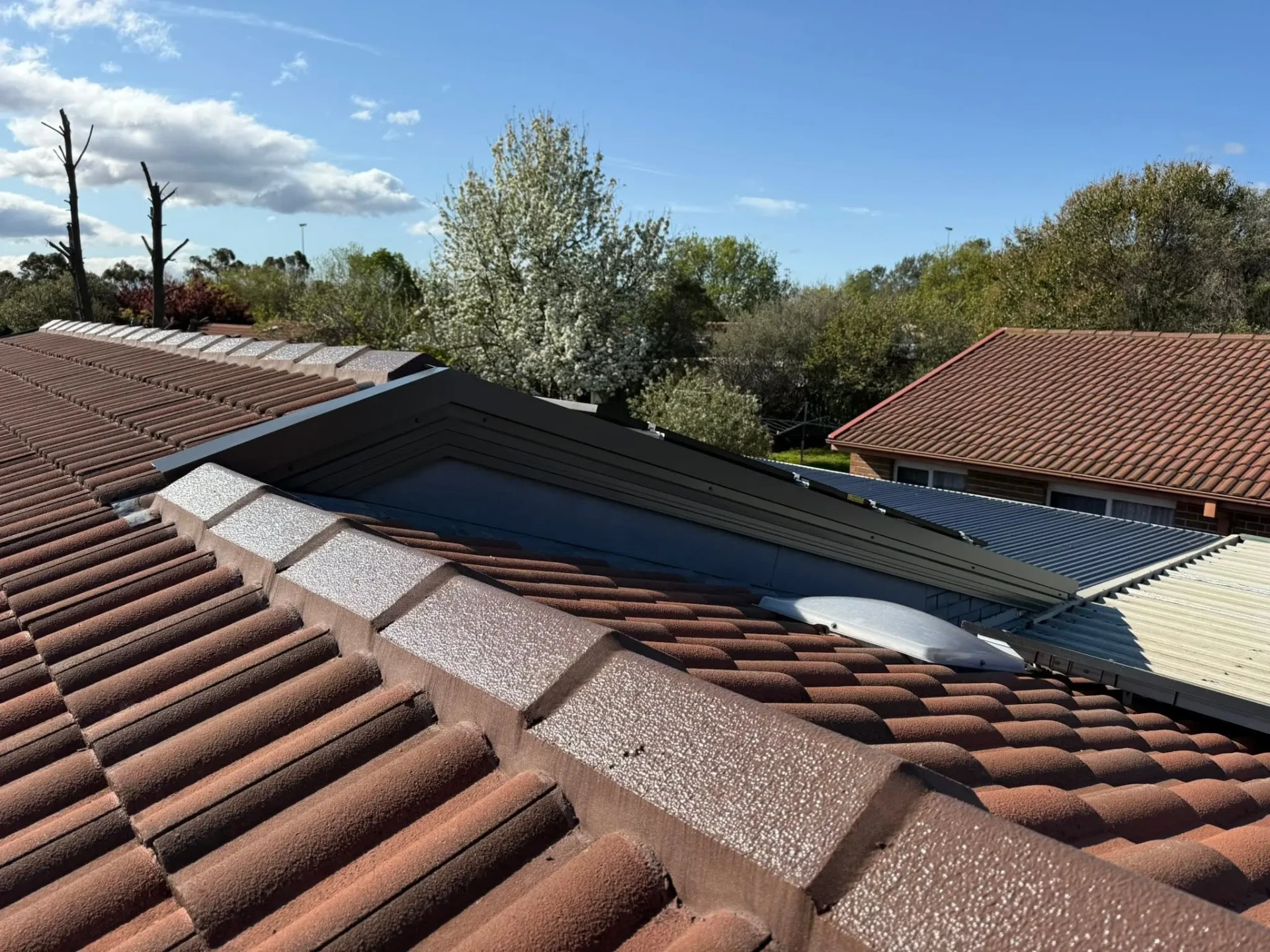 Fresh gable end flashing and ridge line detail on the restored roof